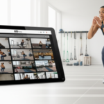 Pessoa realizando exercício funcional com tablet exibindo uma grade de mais de 500 vídeos de treino, simbolizando acesso digital a vasta biblioteca.