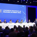 Palestrante no palco do XI Congresso Brasileiro de Direito Penal com audiência atenta e tela exibindo o título do evento.
