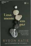 Capa do livro Uma Mente em Paz de Byron Katie sobre uma mesa de madeira